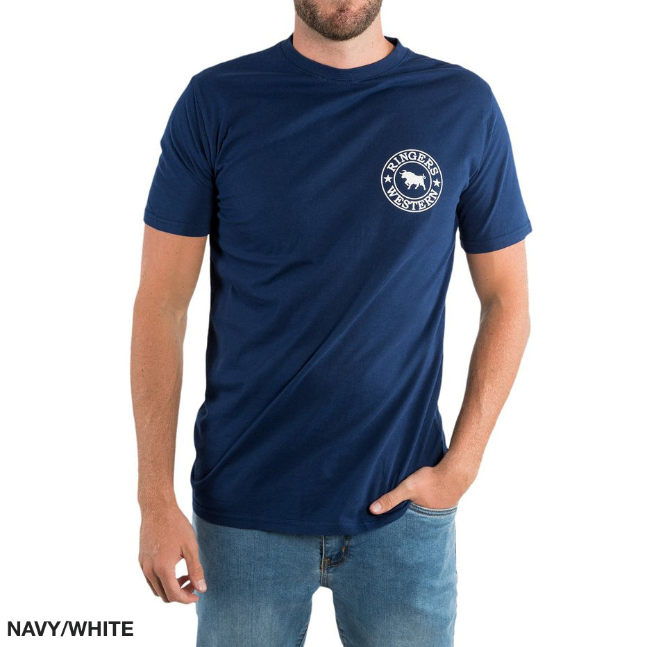 A man wears a Ringers Western Signature Bull Classic T-Shirt, navy with a small white buffalo silhouette logo on the left chest, paired with light jeans. Made of 100% cotton, it features "NAVY/WHITE" text in the bottom left corner.