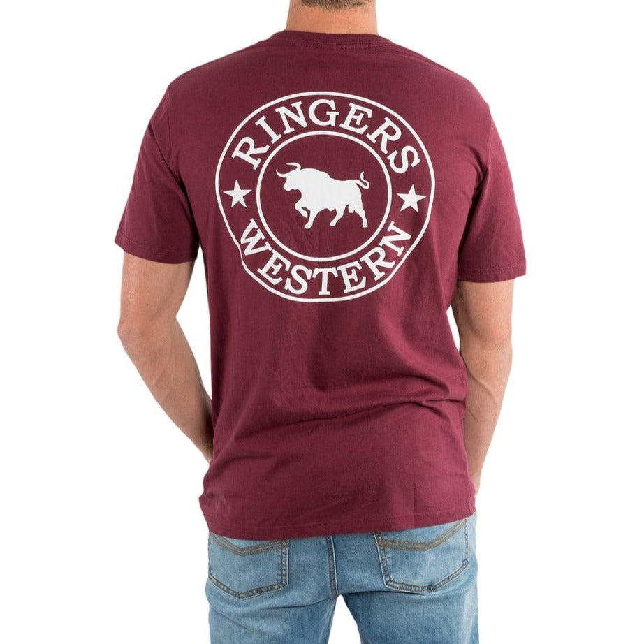 A person wearing a maroon Ringers Western Signature Bull Classic T-Shirt featuring a bold bull and stars logo on the back. The 100% cotton shirt is paired with light blue jeans, showcasing casual charm from behind.