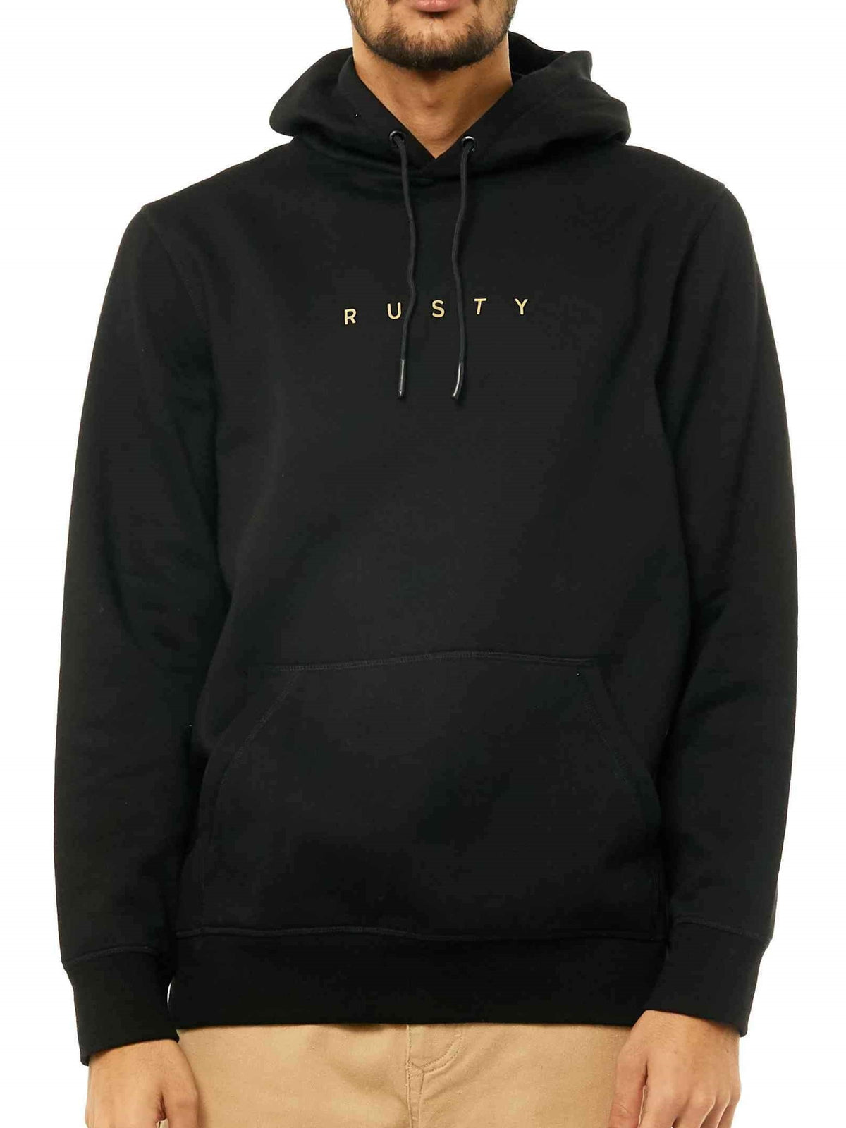 A person wearing the Rusty Short Cut Hooded Fleece in black with gold chest lettering and light-colored pants. The hoodie covers most of their head, and their face is partially out of frame.