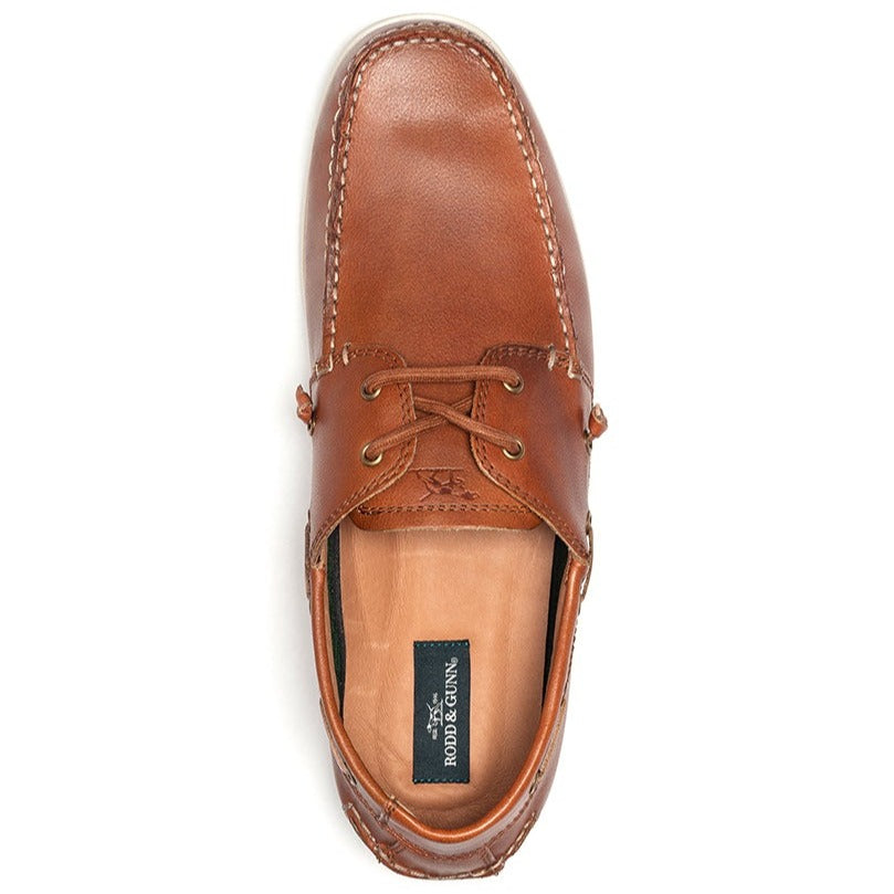 Top view of a single Rodd & Gunn Gordons Bay Boat Shoe in brown leather with laces. The shoe features visible stitching around the toe and sides, a leather upper, and a brand label, "BØRD & GÅRN," on the insole. The rubber outsole ensures good traction.