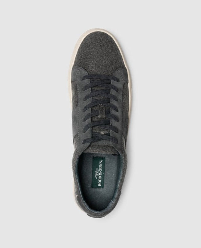 Top view of the Rodd & Gunn Endeavour Sail Sneaker—a single dark gray sneaker featuring suede leather trims and matching dark gray laces, set against a plain light gray background. The sneaker boasts a white sole and a moulded footbed for enhanced comfort, with the inner sole showcasing a green label reading "Rodd & Gunn.