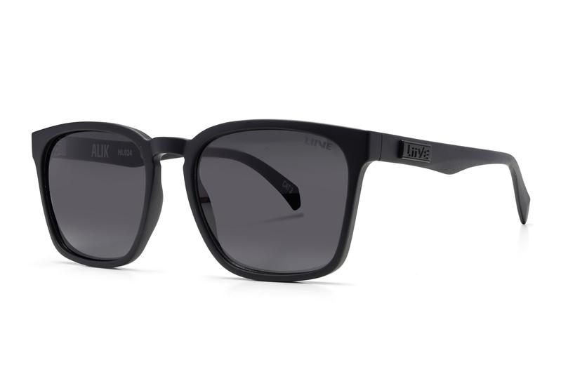 A pair of Liive Alik Sunglasses featuring black square frames, dark UV-protected polycarbonate lenses, and sleek, thick temples. One temple is adorned with a raised logo. The modern, minimalist design makes them ideal for both casual and formal occasions.