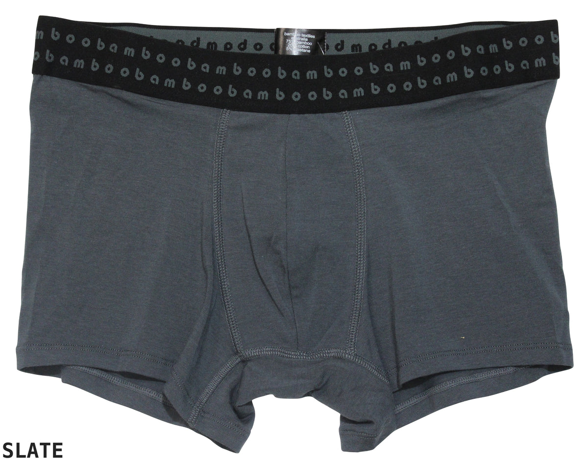 The Bamboo Trunks are gray men's boxer briefs with a black waistband, featuring a repeating "bam" logo in light gray. Made from soft bamboo fabric, these comfortable trunks offer anti-bacterial properties to ensure all-day freshness. The color of the boxer briefs is labeled as "SLATE" in the bottom left corner.
