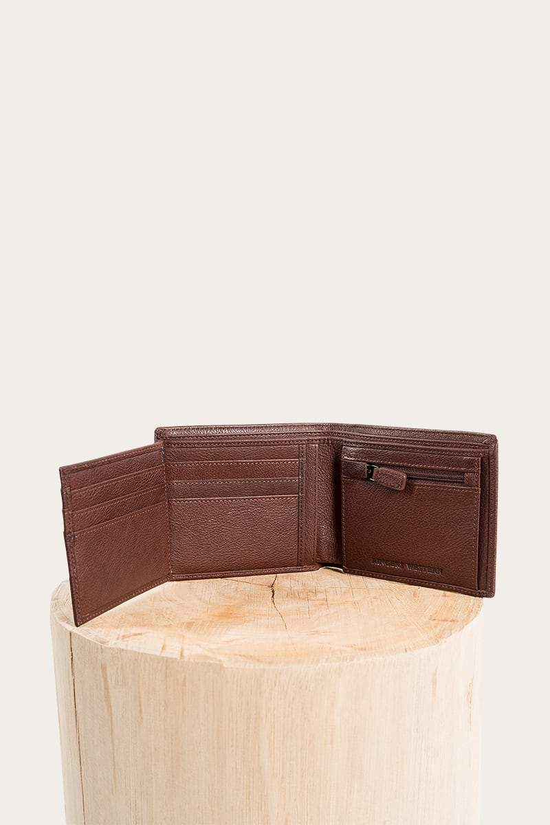 The Ringers Western Bayview Wallet, made from genuine leather, is shown on a wooden surface against a light background. This brown wallet features multiple card slots and a small zippered pocket for convenience.