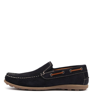 The Colorado Rocana Leather Slip On is a black suede loafer with rawhide lace detailing and white stitching. It features a low heel, textured brown rubber sole, and is designed in a casual slip-on style.