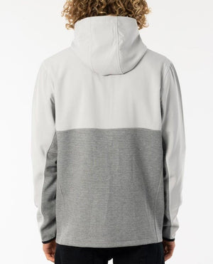 A person with curly hair is seen from the back, wearing a Rip Curl Interblock Hood in light gray and darker gray horizontal stripes. The casual and comfortable hooded jumper appears to provide warmth in cooler weather. The background is plain white.