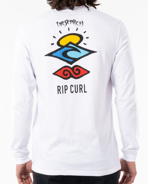 A person wearing a Rip Curl Search Icon Long Sleeve Tee in organic cotton, with bold abstract back graphics of a yellow sun, blue wave, and red swirl, featuring "The Search" and "Rip Curl" in black text.
