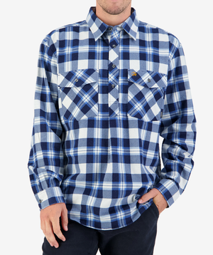 A person wears a Swanndri Egmont Flannelette button-up in blue and white plaid, their hand in the pocket of black pants. This long sleeve shirt has two chest pockets with buttons, though their head is not visible.