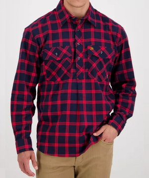 Dressed in the Swanndri Egmont Flannelette, a red and navy blue plaid long-sleeve shirt with buttoned chest pockets and soft brushed cotton, paired with beige pants, a person’s head remains out of view as their right hand rests in a pocket.