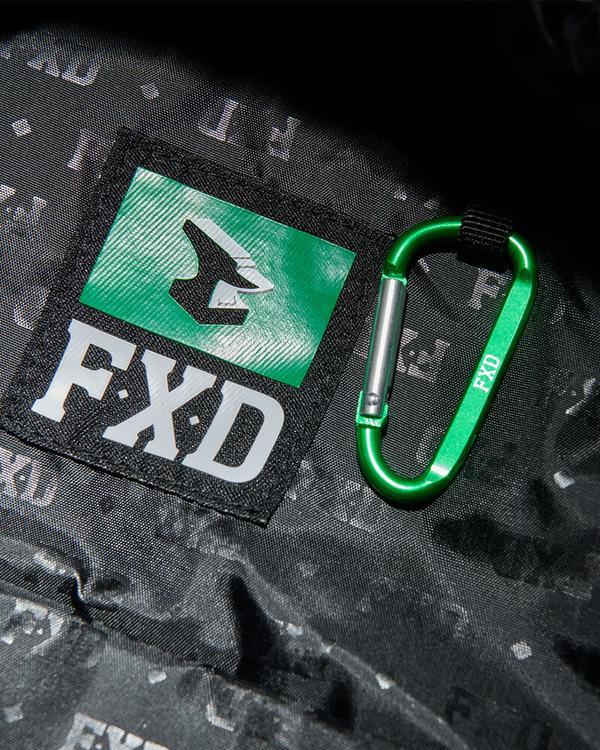 Close-up of a green "FXD" carabiner on a black Cordura Ballistic Fabric surface with a green and black label. The rugged design complements the FXD WBP-3 Work Backpack.