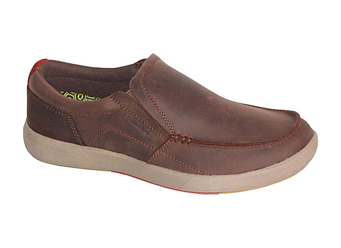 The Slatters Galaxy is a brown casual slip-on shoe featuring a smooth leather upper, visible stitching along the sides, and a light-colored rubber sole with a red accent on the bottom. It includes a memory foam footbed for added comfort, offering both durability and style.