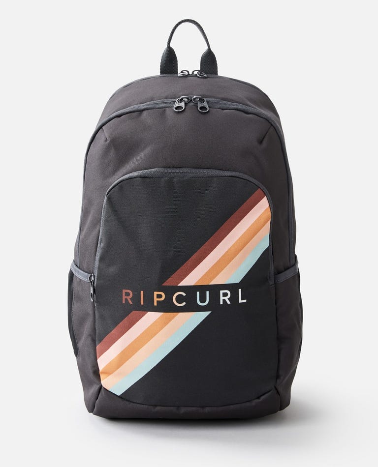 The Rip Curl Ozone 30L Multi Backpack in black showcases a striking rainbow stripe design diagonally across the front pocket, with the "Rip Curl" brand name printed over the stripes. It features multiple zipper compartments, a dedicated laptop section, and a top handle for easy carrying.