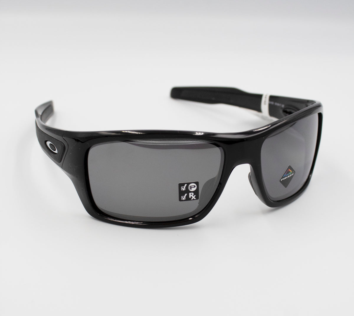 A pair of sleek Oakley Turbine Polarized sunglasses with a glossy black frame. The dark, polarized lenses are reflective, and there is a small sticker with text on the right lens. These sunglasses have a sporty design suitable for casual wear or active use.