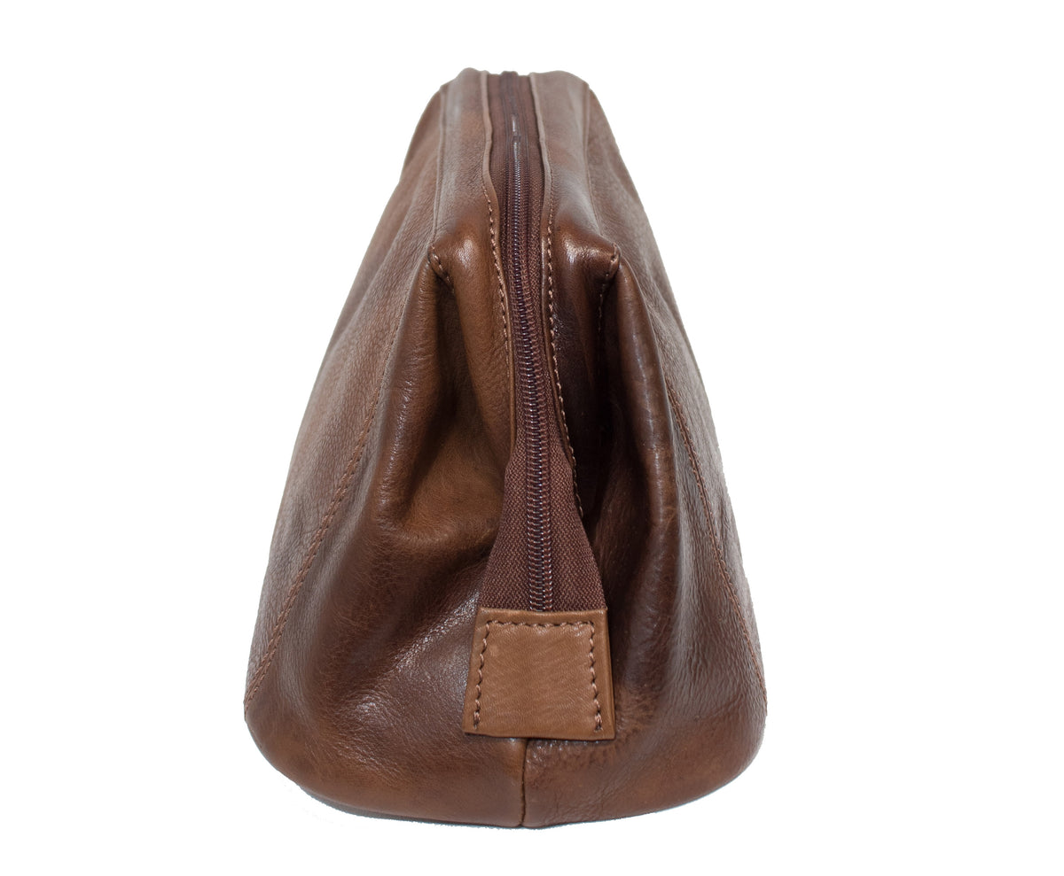 A Pierre Cardin Leather Toiletry Bag stands upright, showcasing its genuine brown leather texture. The zippered pouch features visible stitching and a zipper running from the top front to the bottom. This simple, rectangular bag perfectly combines elegance with functionality.