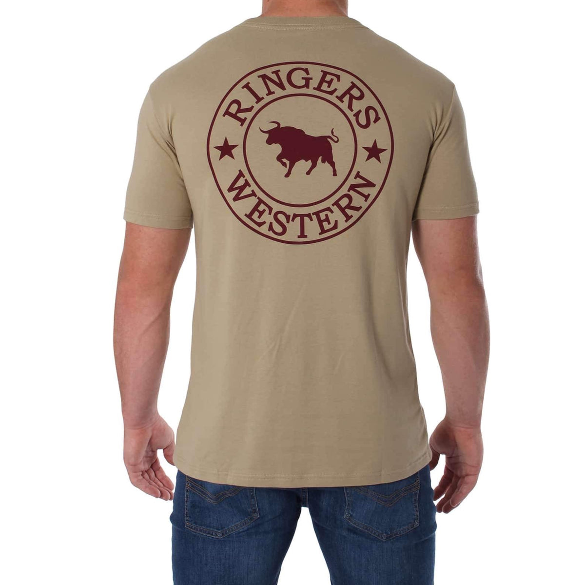 A person facing away is dressed in the Ringers Western Signature Bull Classic T-Shirt, a comfortable beige crew neck with a red printed logo on the back featuring a bull and the text "Ringers Western." They are also wearing blue jeans against a plain white background.