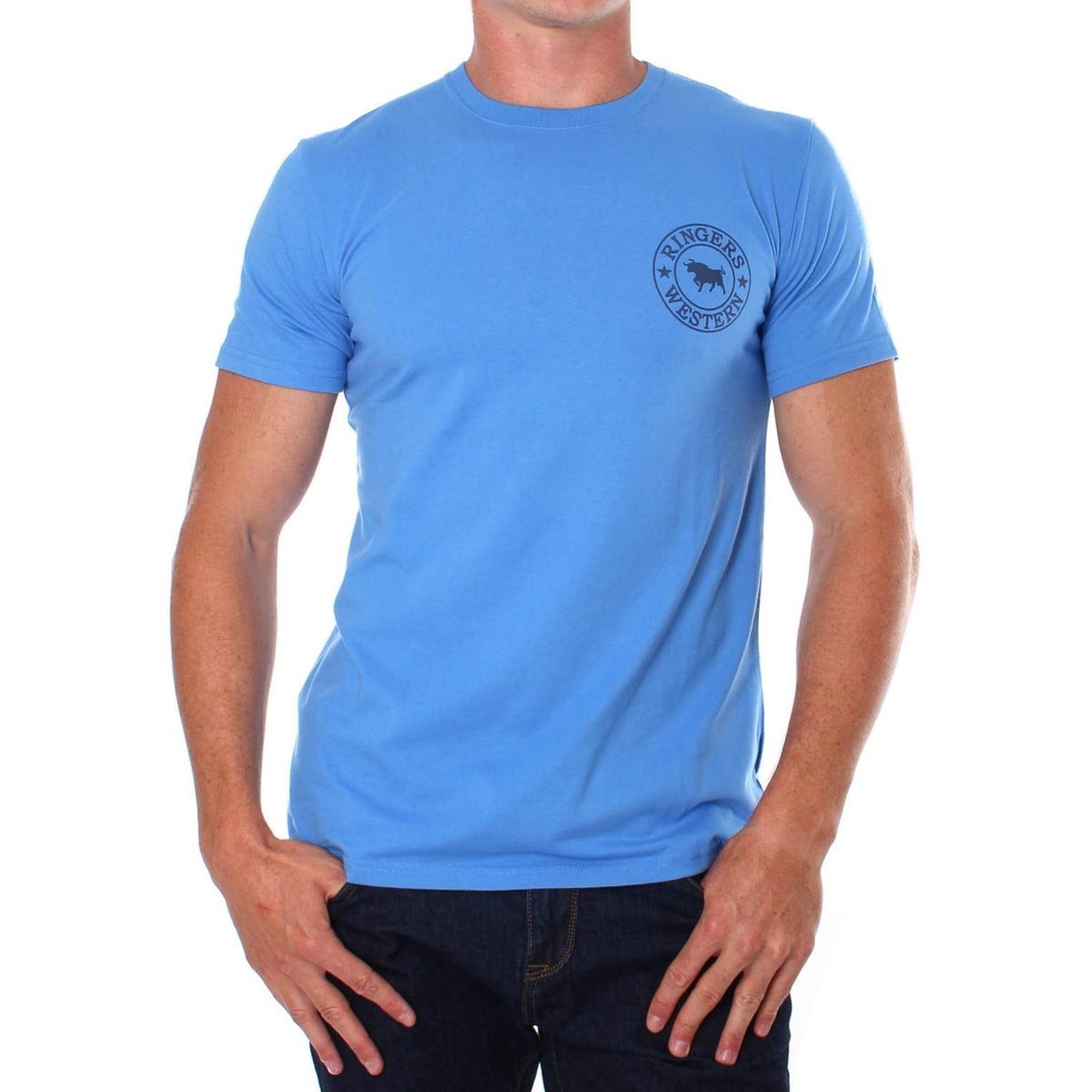 A person wearing a comfortable light blue Ringers Western Signature Bull Classic T-Shirt with a crew neck and a circular logo on the left chest that reads "Ringers Western" and features a cow silhouette. The person is also wearing dark blue jeans and standing against a plain white background.