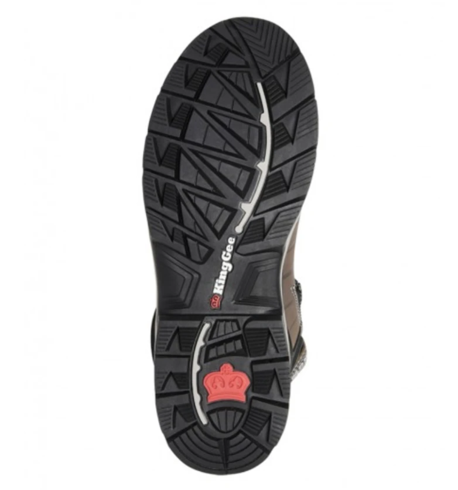 Close-up view of the outsole of a black and brown King Gee Quantum Safety Boot. The outsole features a rugged tread pattern for enhanced grip and durability, with shock-absorbing protection. The boot displays the brand name "KingGee" along the center and a red crown logo near the heel.