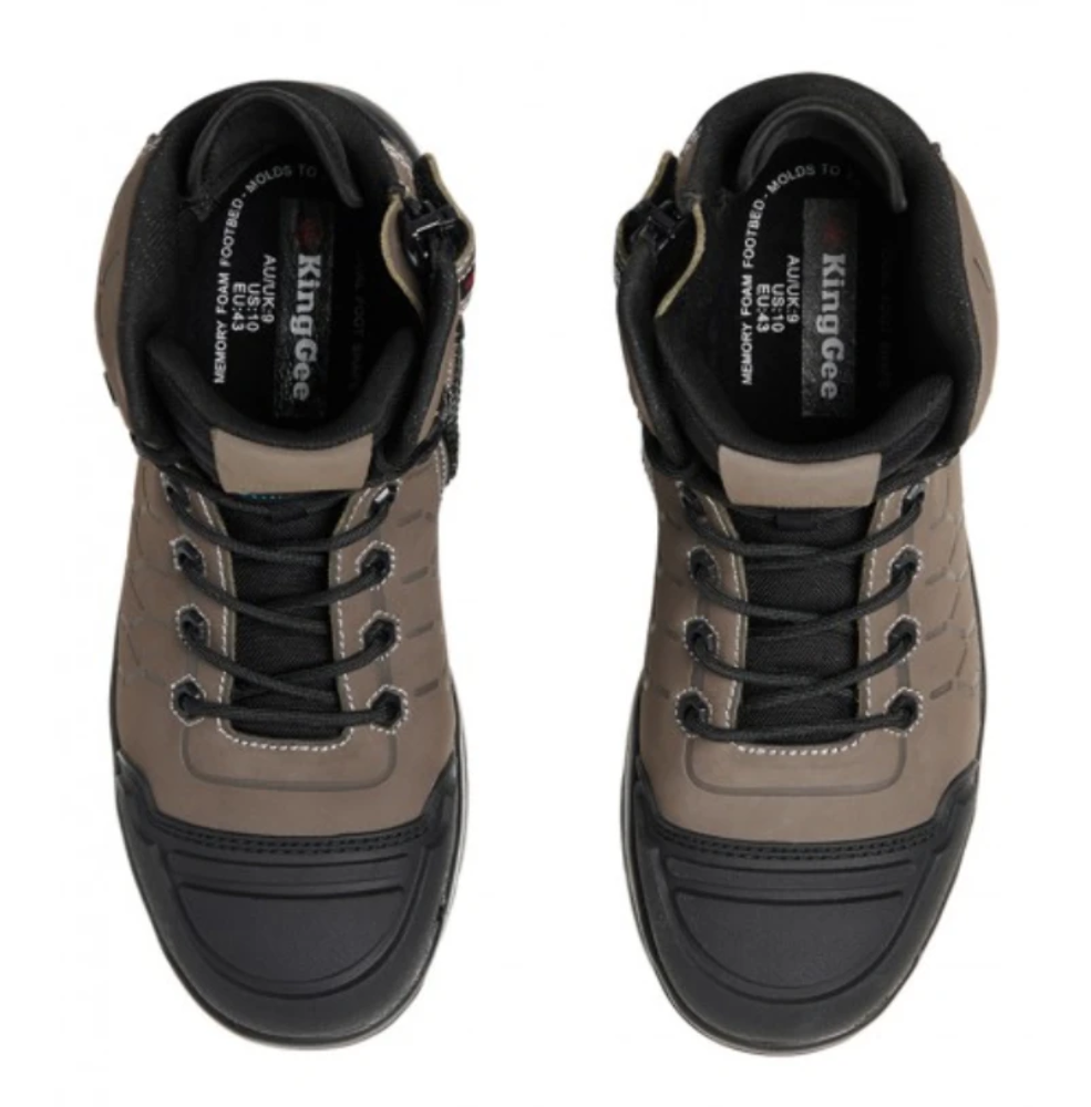 A pair of King Gee Quantum Safety Boots. These men's work boots are beige with black accents, featuring black laces, reinforced black toe caps, and a rugged sole designed for durability and shock-absorbing protection. The interior labels display the KingGee brand name and shoe size information.