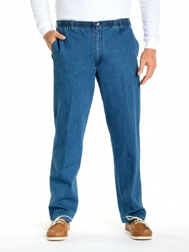 A person wearing Breakaway Ipswich Denim Jean with a mid-rise design, a white long-sleeve shirt, and brown boat shoes stands against a white background with one hand in their pocket.