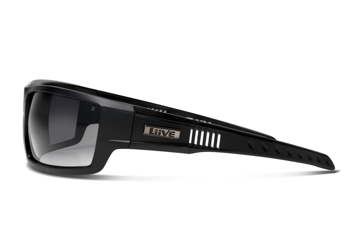 The Liive Z Saw Safety Sunglasses feature a sleek design with thick frames and tinted polycarbonate lenses offering UV protection. The wide arms have vertical slits and display a metallic emblem with the brand name "Liive.