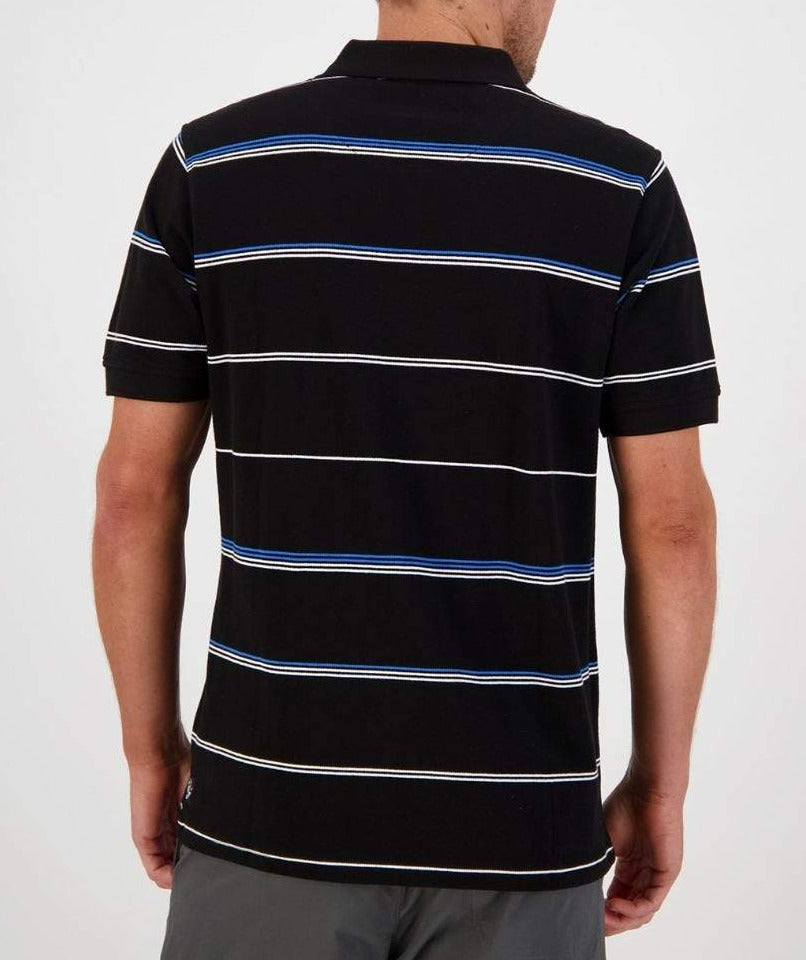 Back view of a person wearing the Swanndri Concord Stripe Polo in black, featuring short sleeves and horizontal stripes in white and blue. Made from 100% cotton, the shirt displays the Swanndri logo. The individual is standing with arms relaxed at their sides against a plain background.