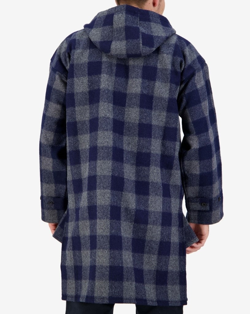 A person is wearing the Swanndri Original Lace Front Bush Shirt, a long, hooded coat in blue and gray checkered plaid made of 100% wool. The shirt features buttoned cuffs and is shown from the back, emphasizing its weatherproof design and impressive length.