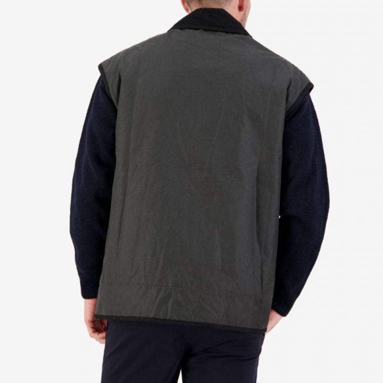 A person faces away, wearing a Swanndri Foxton Vest Wool Lined in dark green over a long-sleeve black sweater, against a plain white background.
