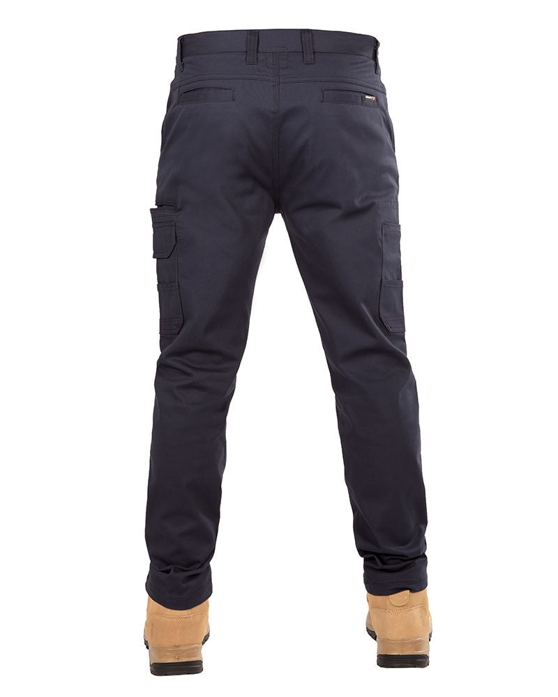 Rear view of a person wearing UNIT Demolition Stretch Cargo Pant in navy blue with UPF 50+ protection and light brown work boots. The durable work pant features multiple pockets, including cargo-style flap pockets on the sides of the thighs. The person's upper body is not visible.