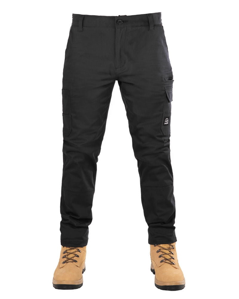 A person wearing black UNIT Demolition Stretch Cargo Pants with multiple cargo-style pockets and tan work boots stands facing forward. The durable work pants feature a button closure, ensuring both style and functionality.
